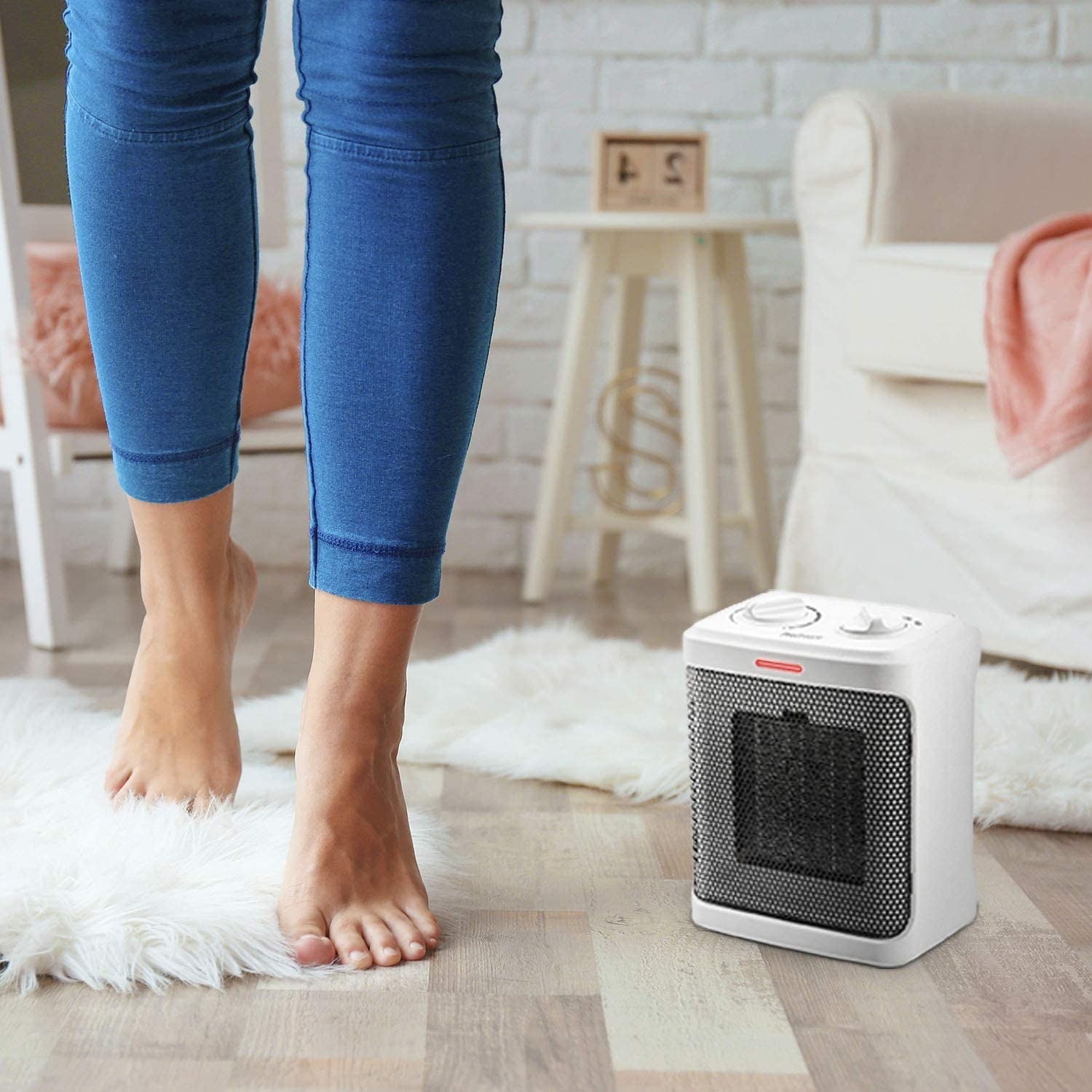 A person walking by the space heater on the floor of a living room