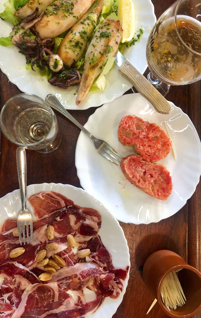 Plates of Spanish tomato bread, jamon iberico, and grilled squid.