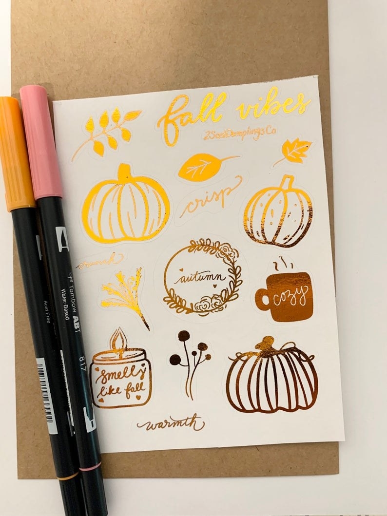 A  gold foil sticker sheet filled with autumn objects, pumpkins, candles, flowers, steaming mug