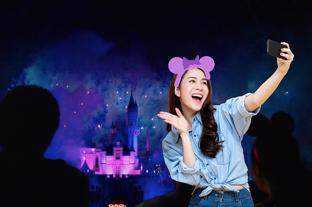 a woman wearing Mickey ears and taking a selfie at the castle fireworks