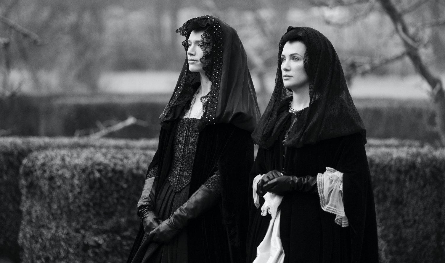 The Haunting of Bly Manor still: in black and white, Perdita and Viola sisters stand in period clothes symbolizing mourning