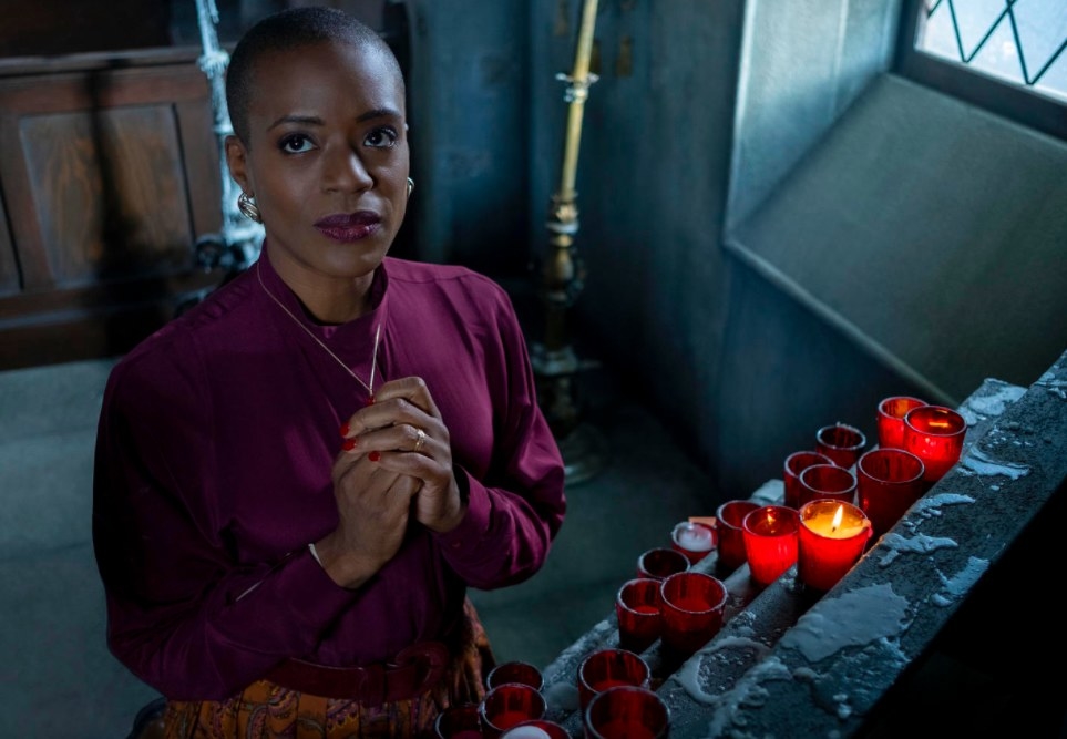 Still from The Haunting of Bly Manor: Hannah prays in front of lit candles at the chapel