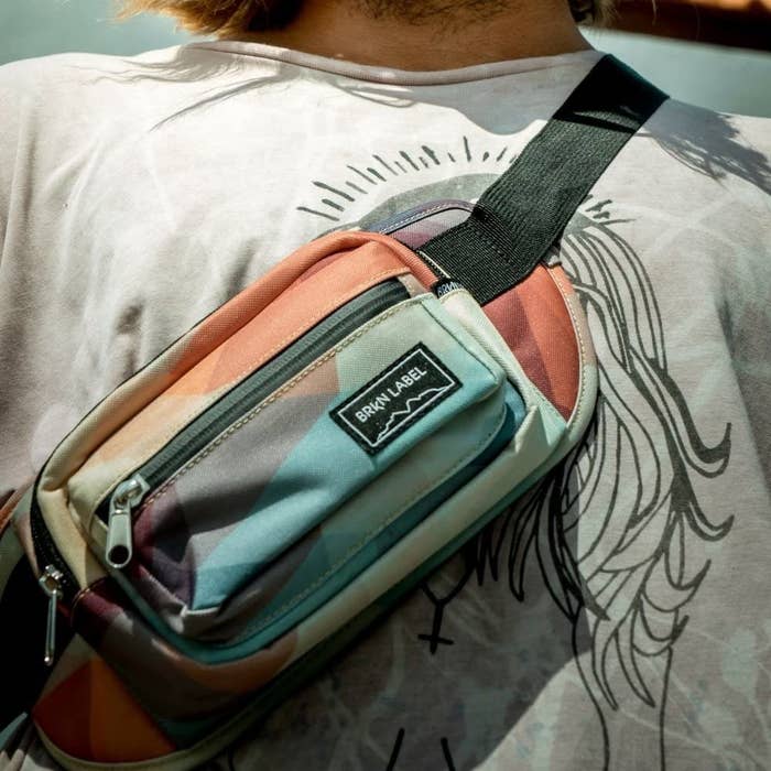 A close up of a person wearing the belt bag slung across their shoulder