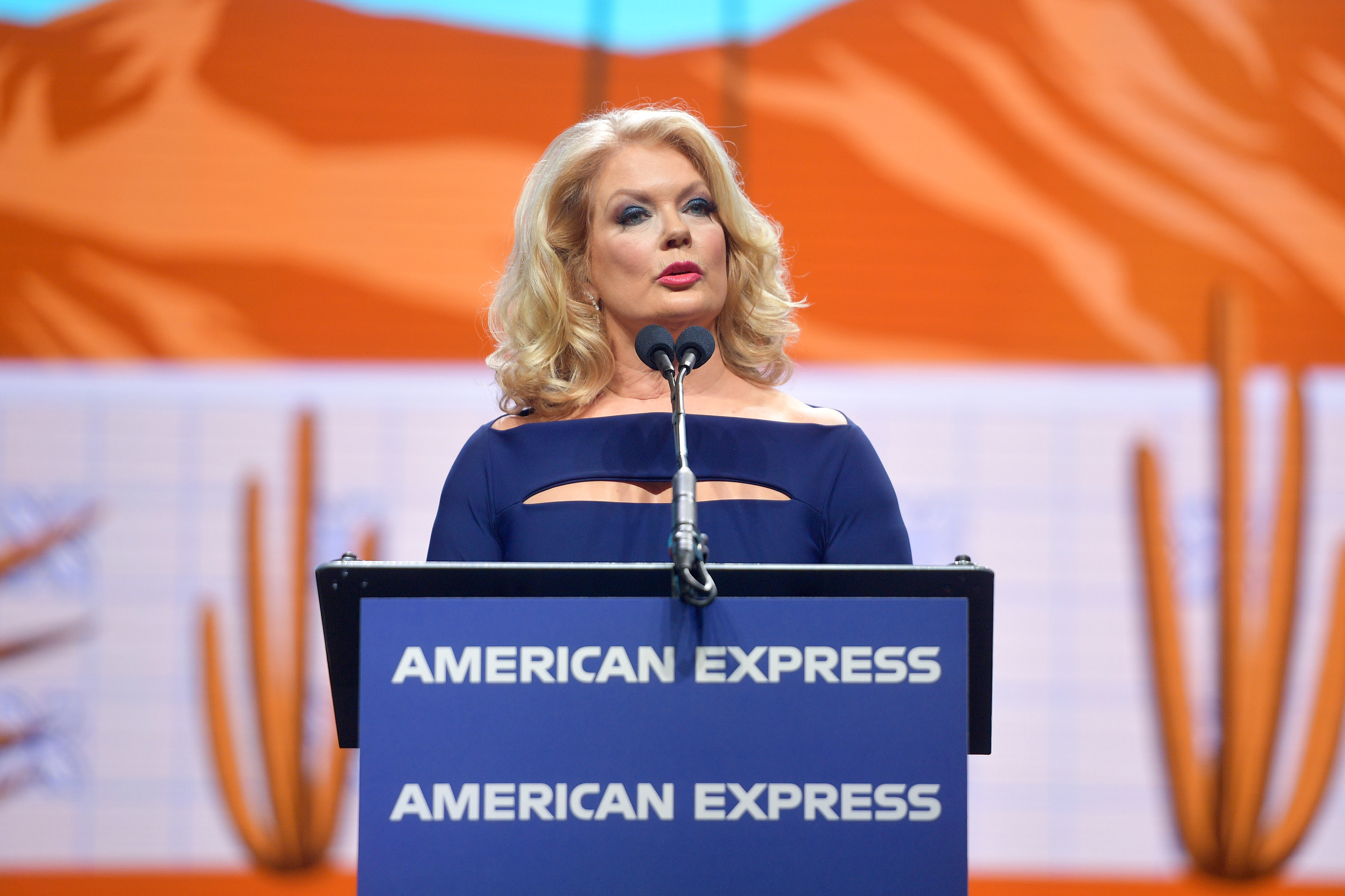 Mary standing at a podium speaking at an event