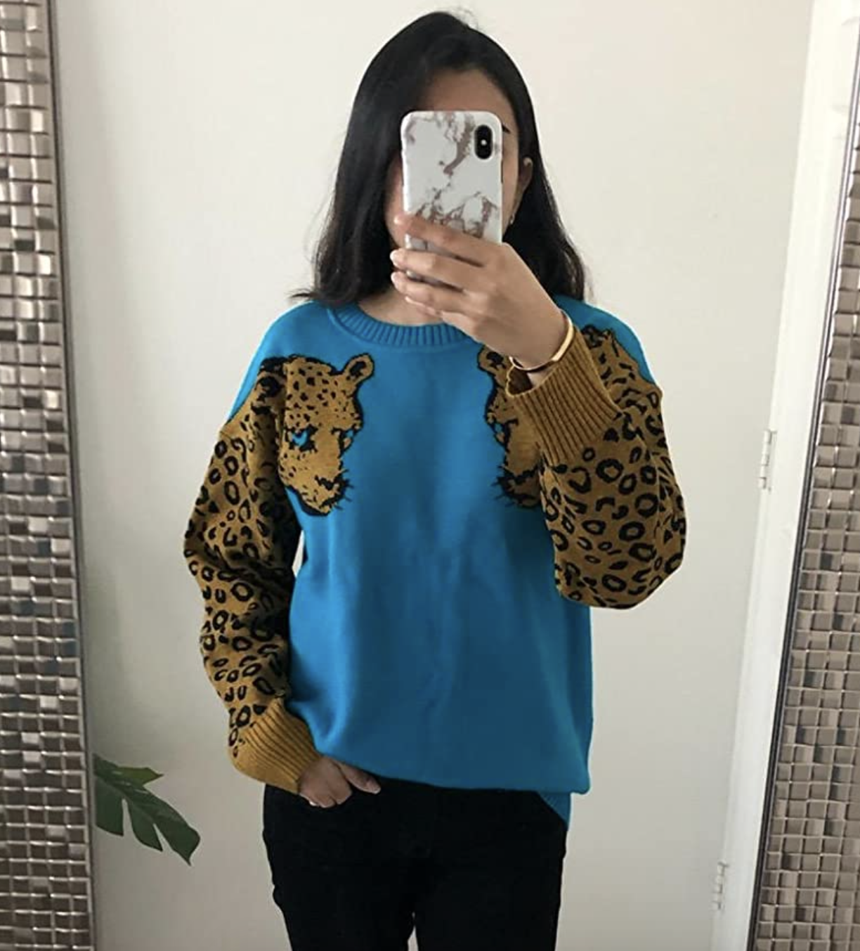 reviewer wearing the blue sweater with leopard illustration on sleeves