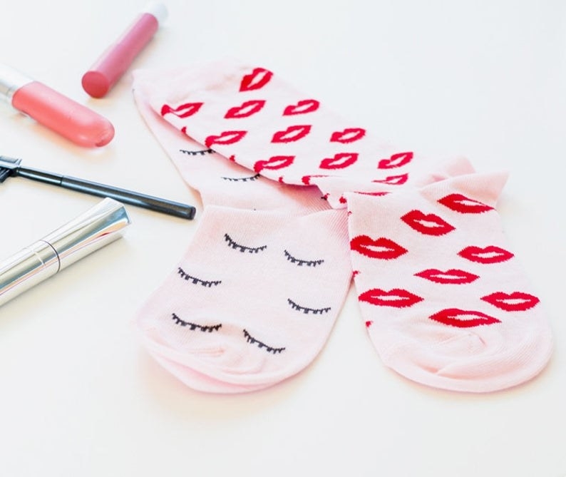 A pair of socks one with kisses and the other with eyelashes