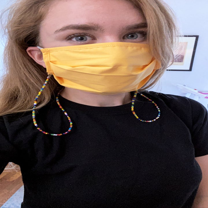 Emma wearing a yellow face mask with a rainbow beaded chain