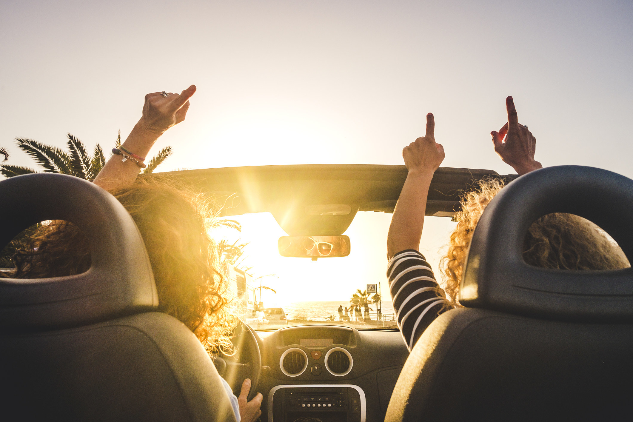 photo of two people enjoying their car ride with their hands in the air