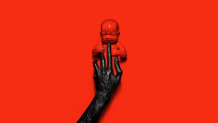 A creepy clawed hand playing with a bloody baby