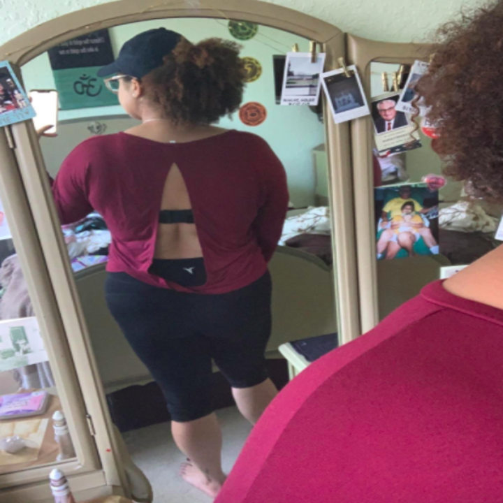 Reviewer shows open back view of the same top while wearing a black sports bra
