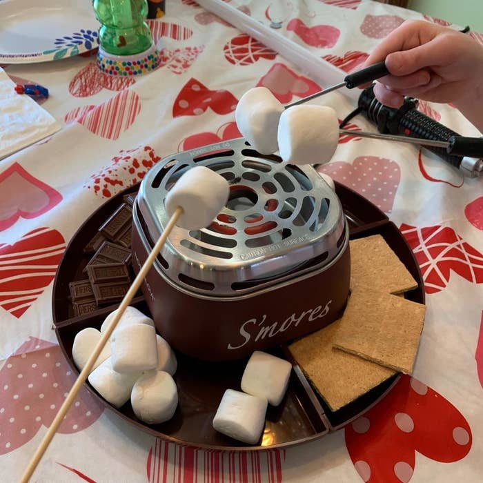 A reviewer&#x27;s s&#x27;mores maker in use with marshmallows, chocolate, and graham crackers in the tray