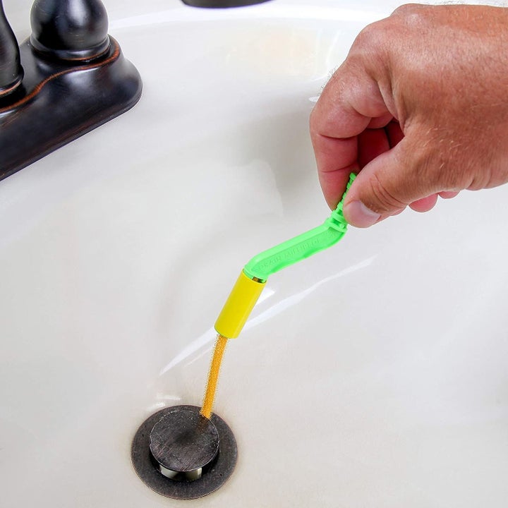 a yellow flexisnake tool being inserted into a sink drain