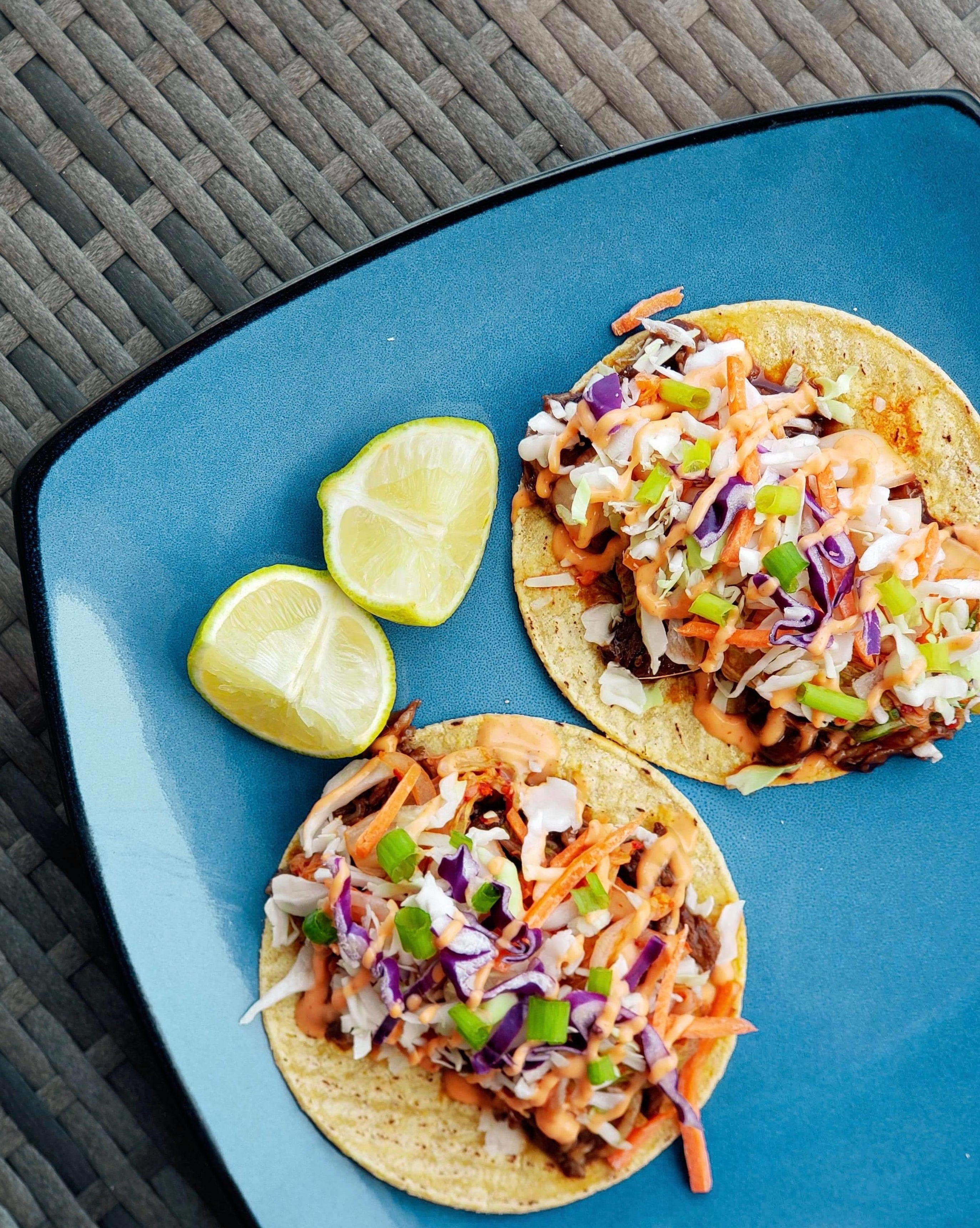 The same plate showing the two Korean tacos and lime wedges from a different angle