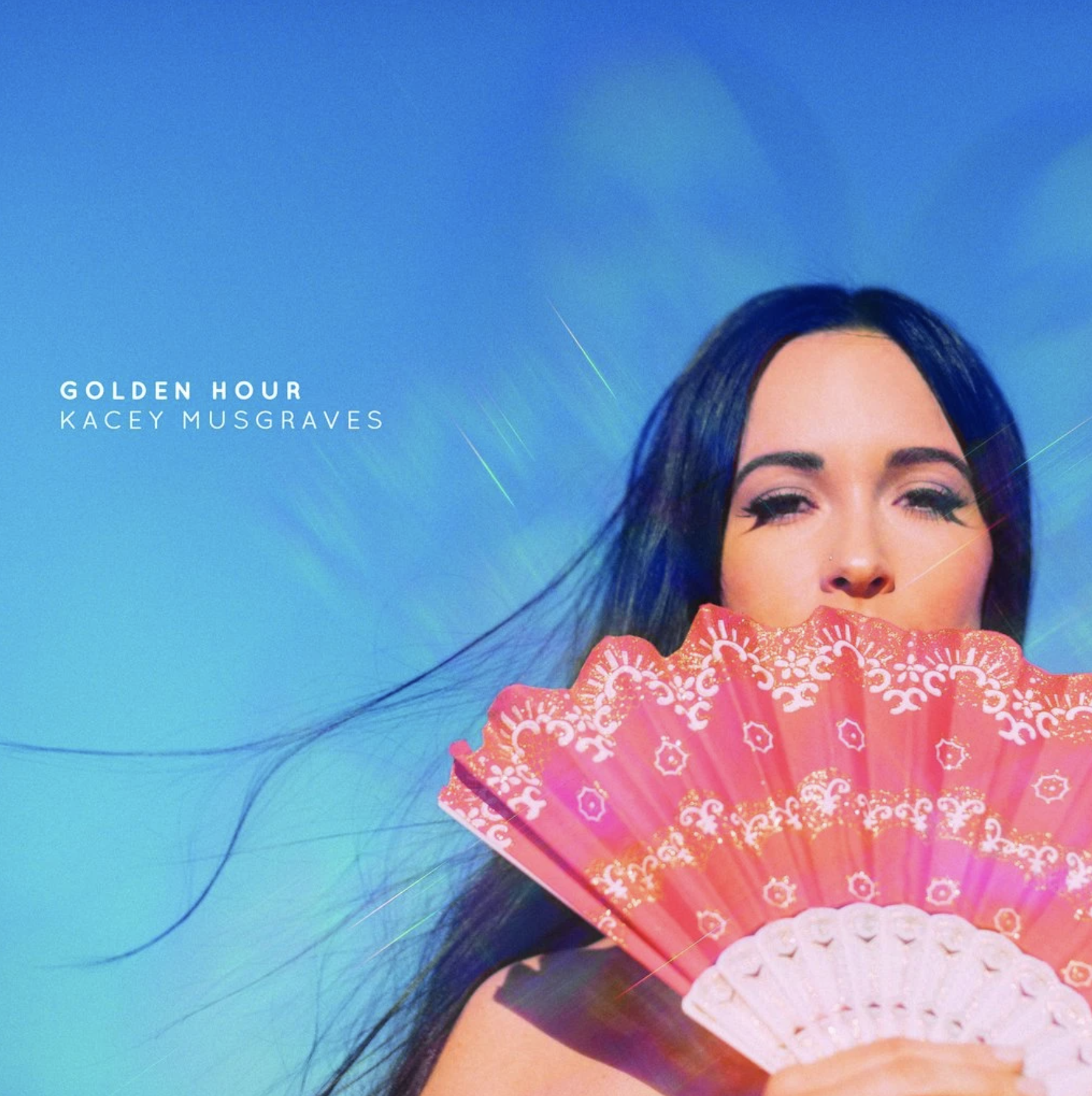 Kacey Musgraves with her hair blowing in the wind and a fan in front of her face. 