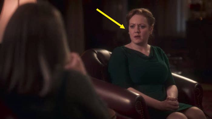 One of the wedding guests from "Haunting Of Bly Manor" sitting down on a chair; she is wearing a green dress and has blonde hair