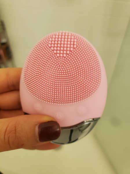 A reviewer holding the vibrating facial cleanser in pink