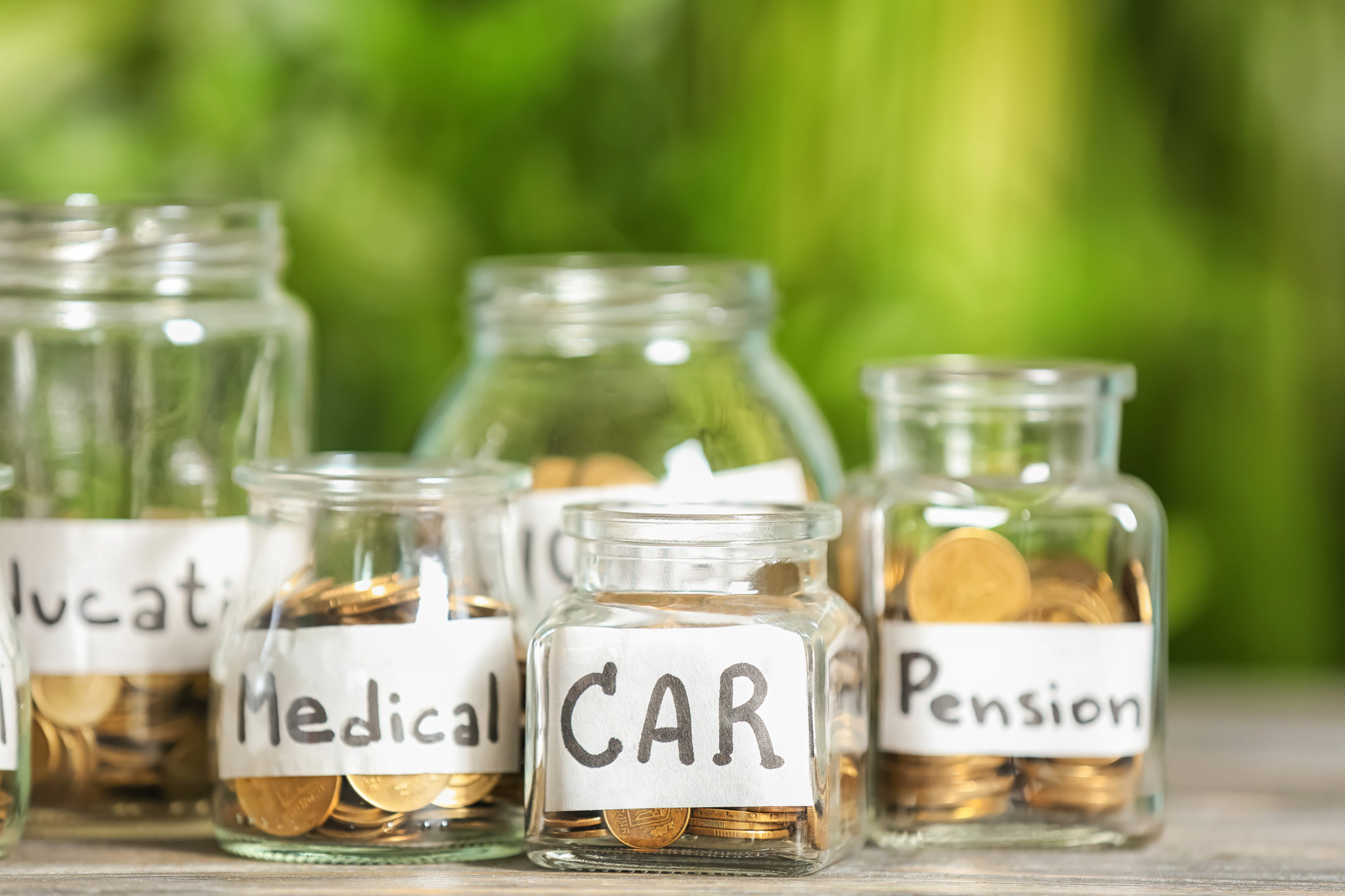 Jars labeled &quot;car,&quot; &quot;medical,&quot; and &quot;pension&quot; with coins inside