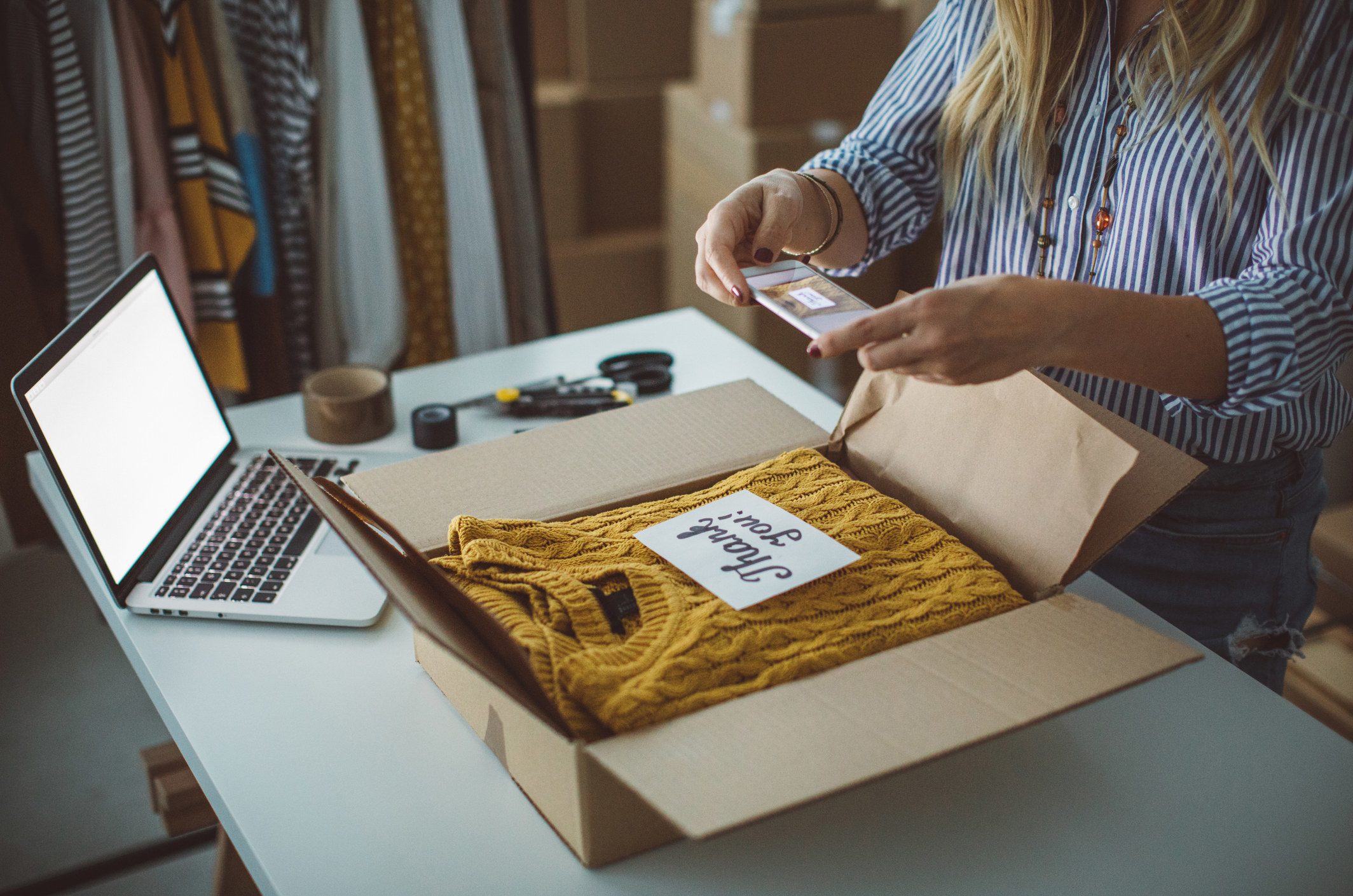 A person taking a photo of a sweater they are selling