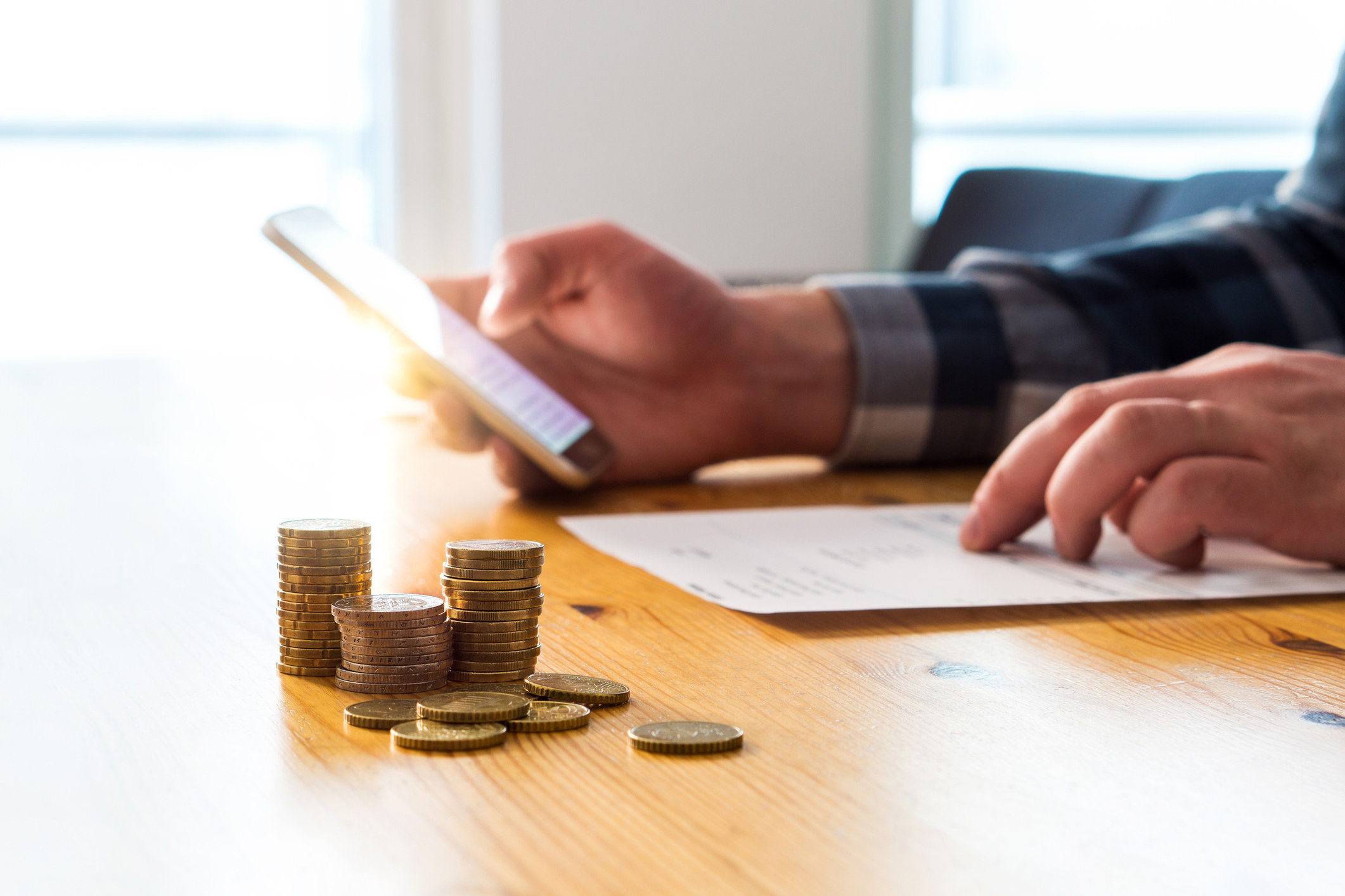 A person holding a phone and going through a bill statement