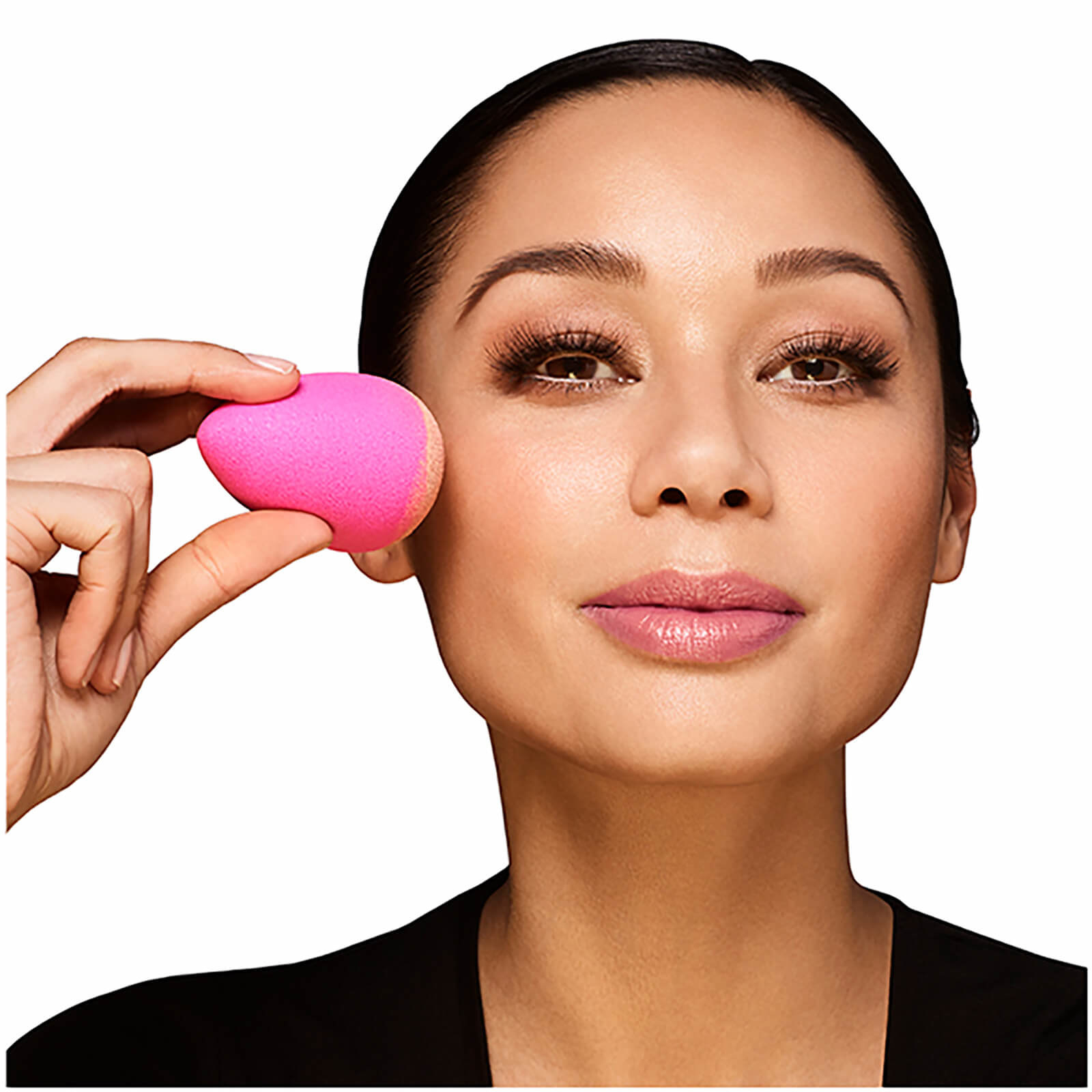 A person using the palm-sized, egg-shaped BeautyBlender to blend makeup