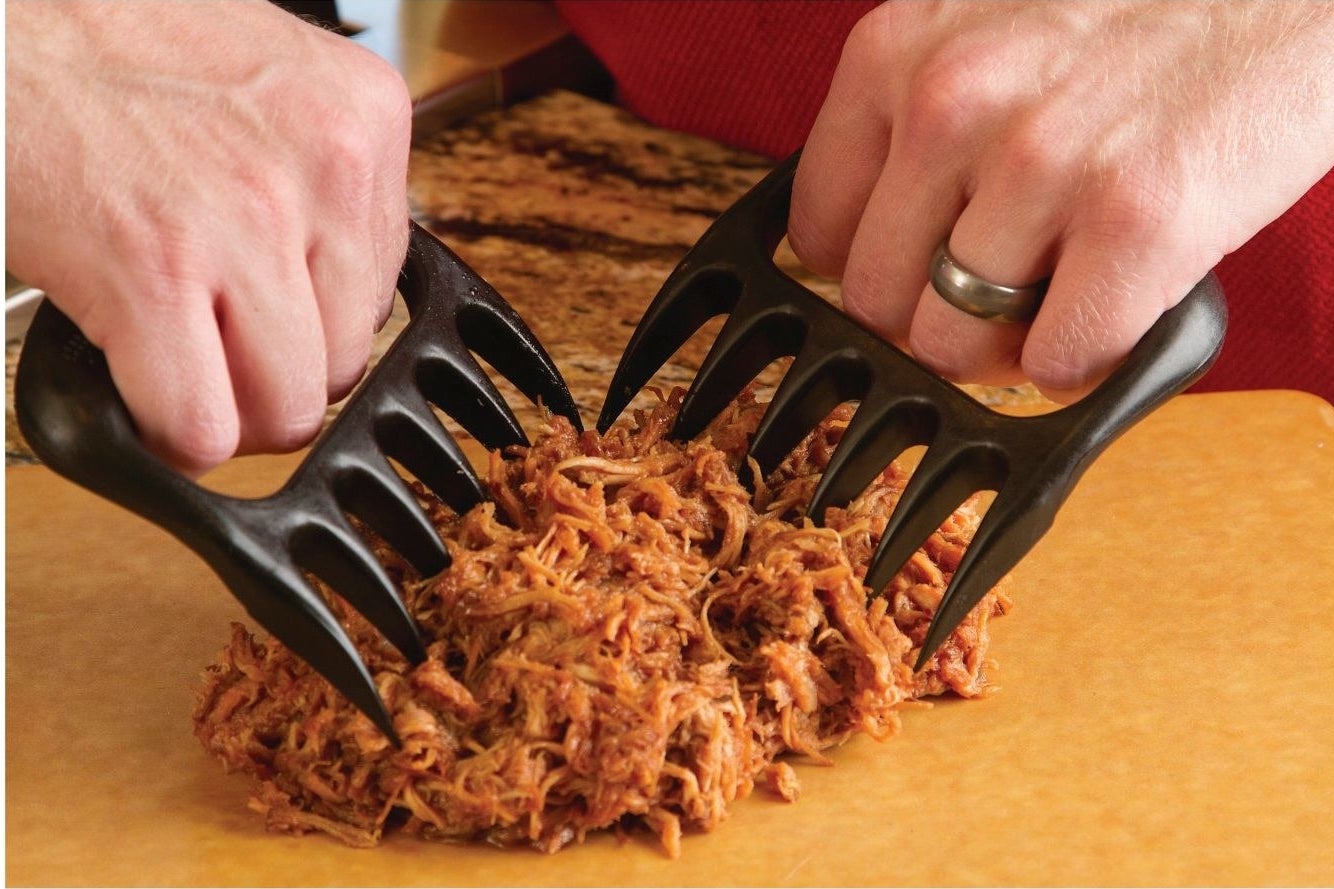 person using black bear paw meat handles to shred meat