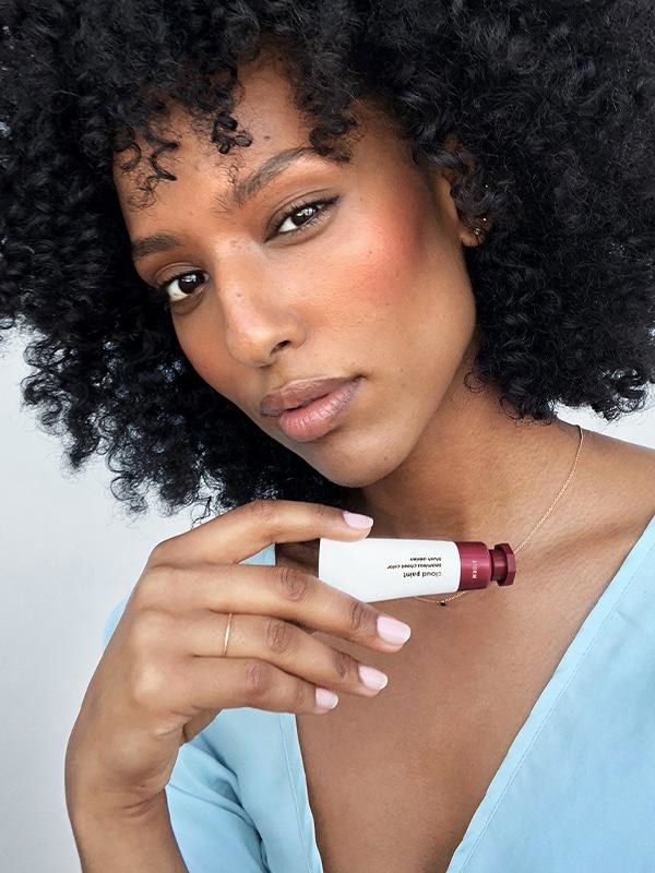 Model wears Glossier Cloud Paint in Storm shade on their cheeks
