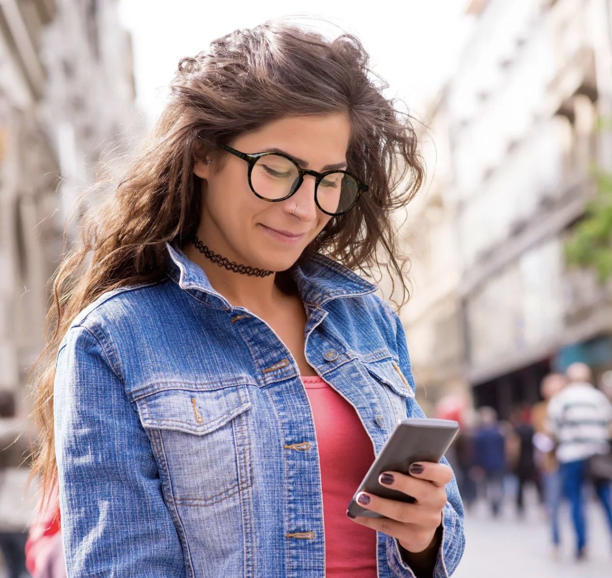 a model wears blue light glasses while scrolling through their phone 