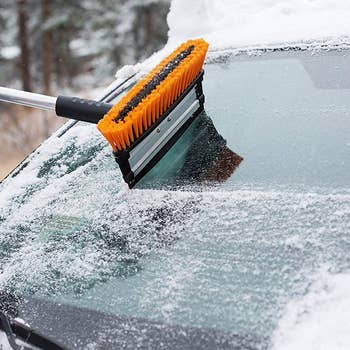 Model using the ice scraper to clear the back windshield of a car