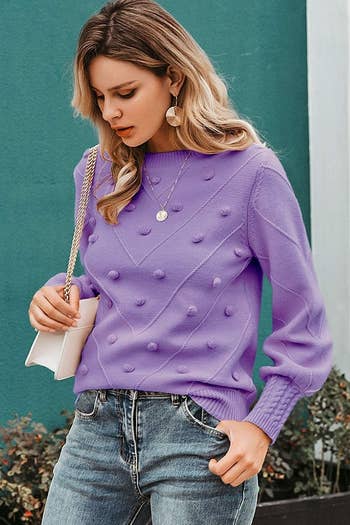 A model wearing the sweater in purple with jeans