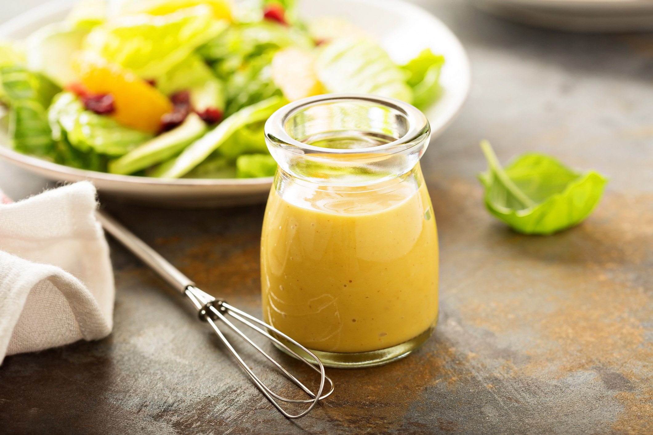 A jar of dressing with a salad