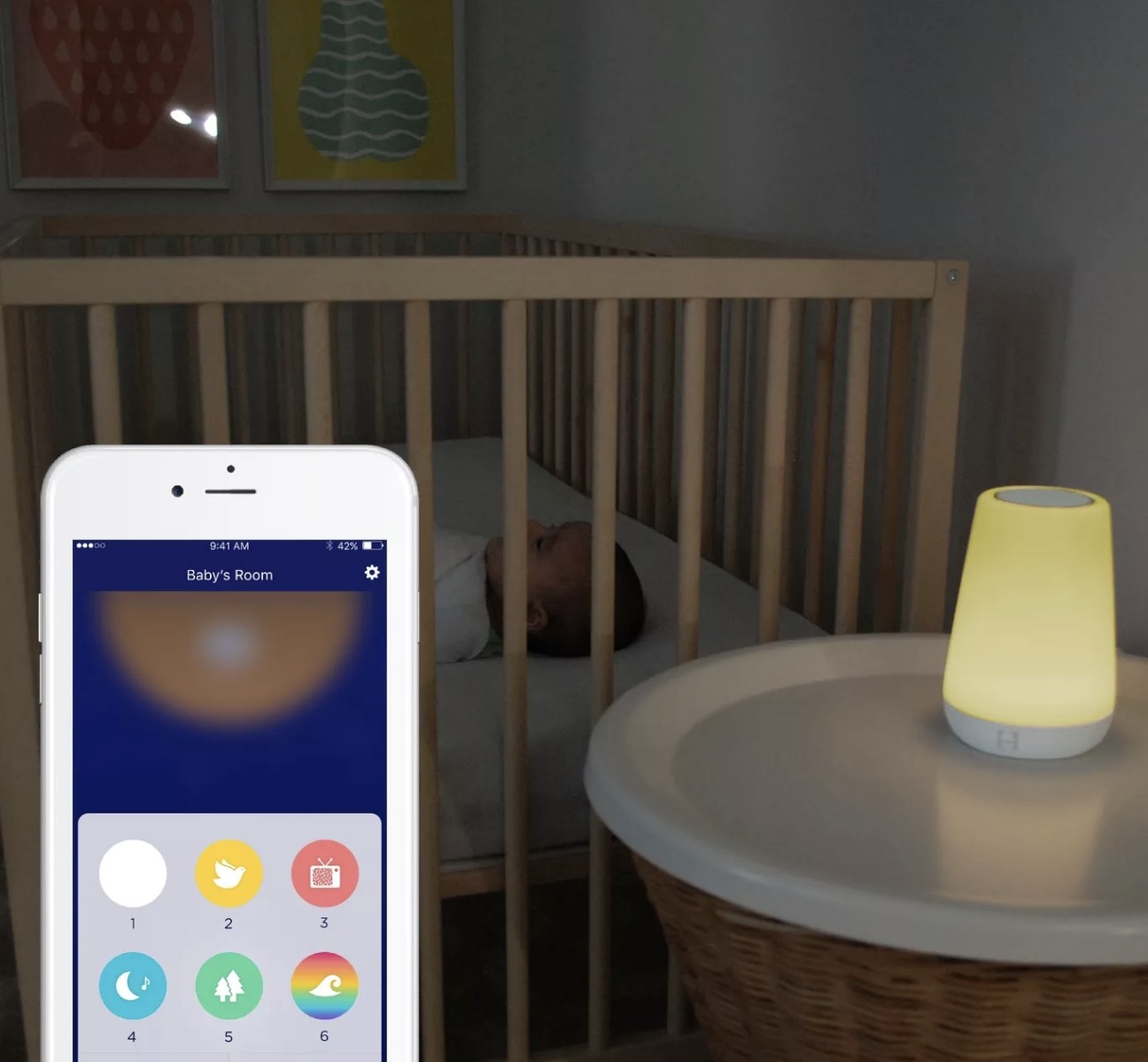 a yellow hatch sound machine next to a baby crib, connected to an app on an iphone