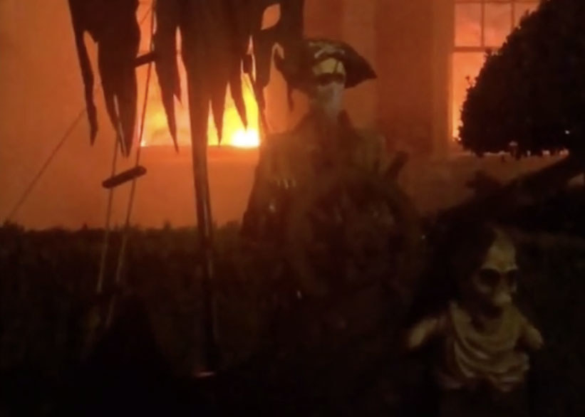 A house that appears to be on fire with a pirate skeleton in the foreground