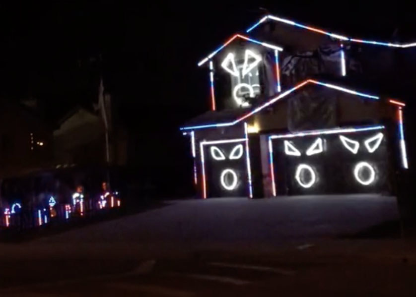 A house lit up with neon faces on the garage and windows 