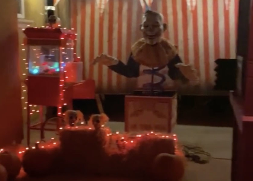 A giant clown jack-in-the-box sits next to a popcorn machine covered in orange lights