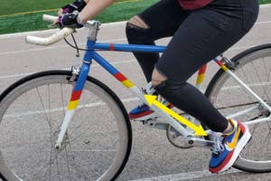 A person riding a bike with shoes that have the same exact color scheme as their bike.