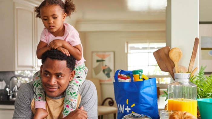 A young child resting on their parent's shoulders in a kitchen