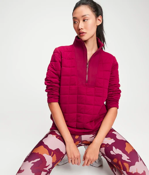 A kneeling person wears the quilted half-zip sweater with matching sporty leggings