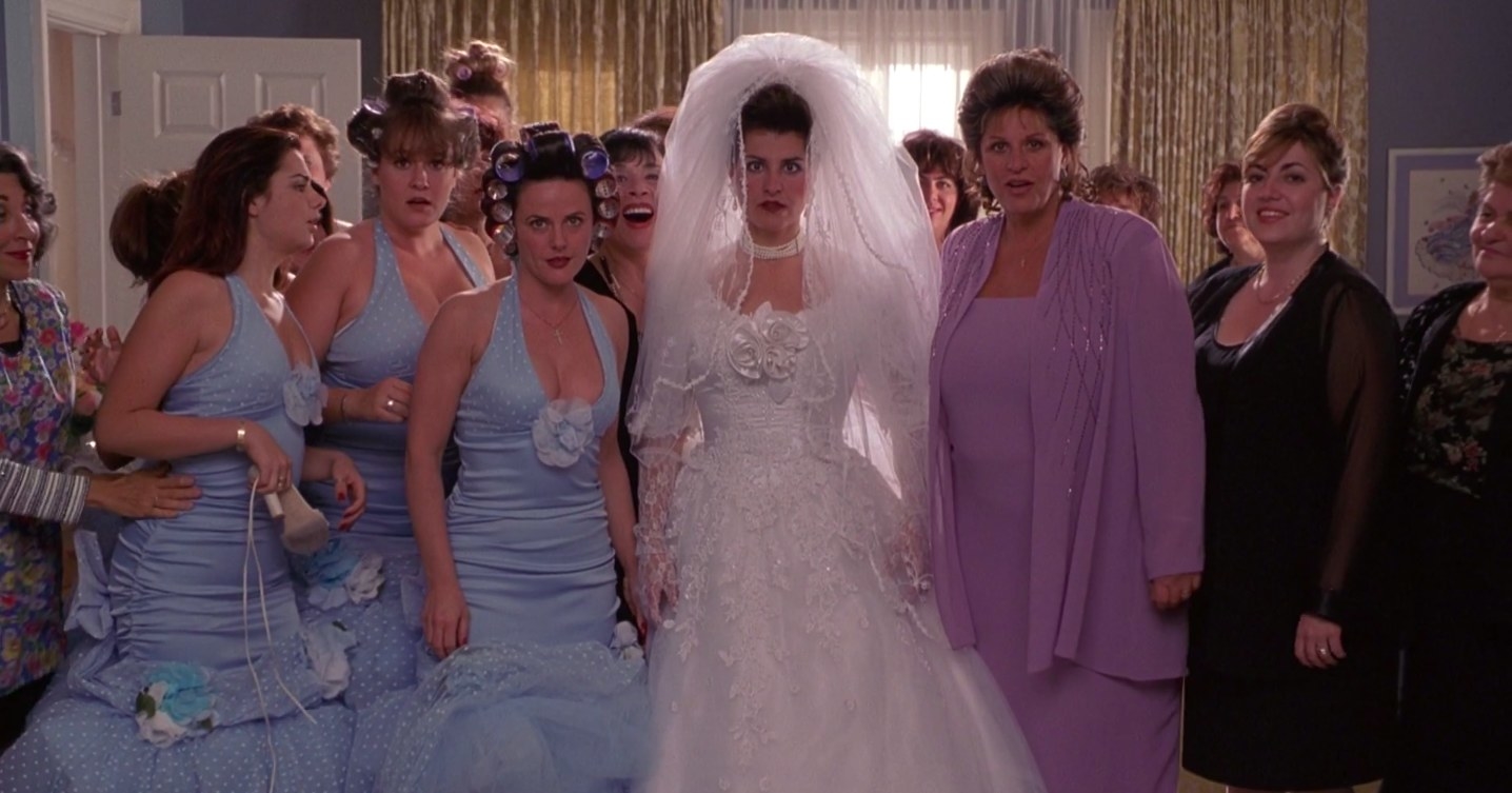 Toula dressed in a wedding dress next to her mother and bridesmaids in "My Big Fat Greek Wedding"