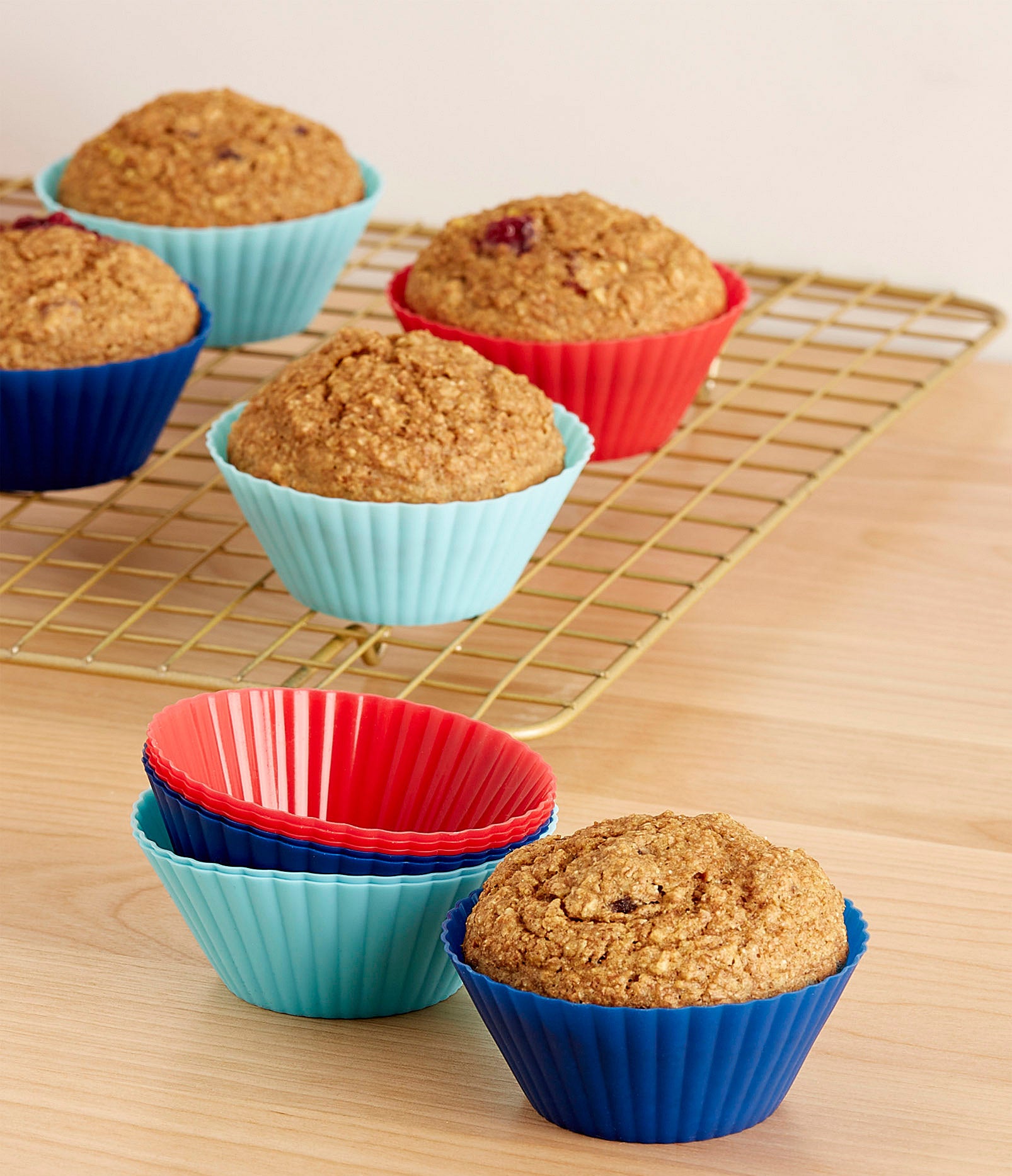 A set of silicone muffin liners with muffins on a baking rack