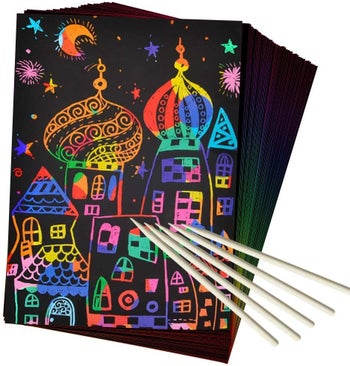 the scratch art with a rainbow castle on it and wooden drawing utensils