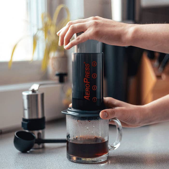 A person using an Aeropress in their kitchen
