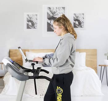 A personal walking on a treadmill with their laptop propped in front of them 