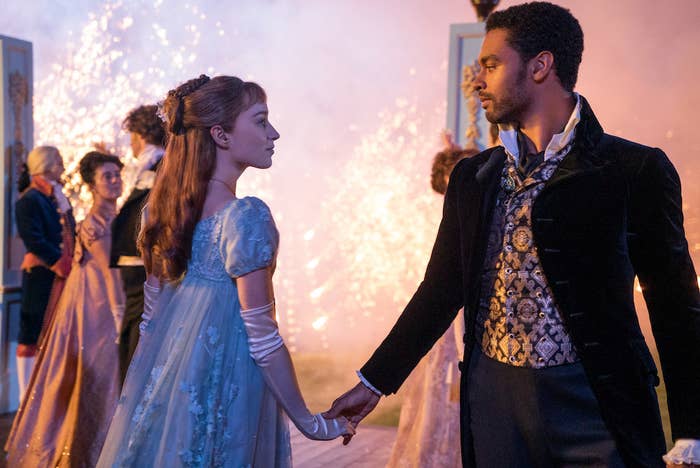 Daphne and Simon holding hands at a grand ball. 