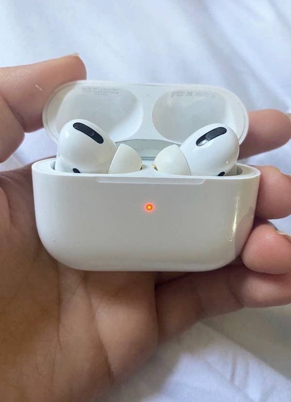 Hand holding the wireless earbuds in case, both in white