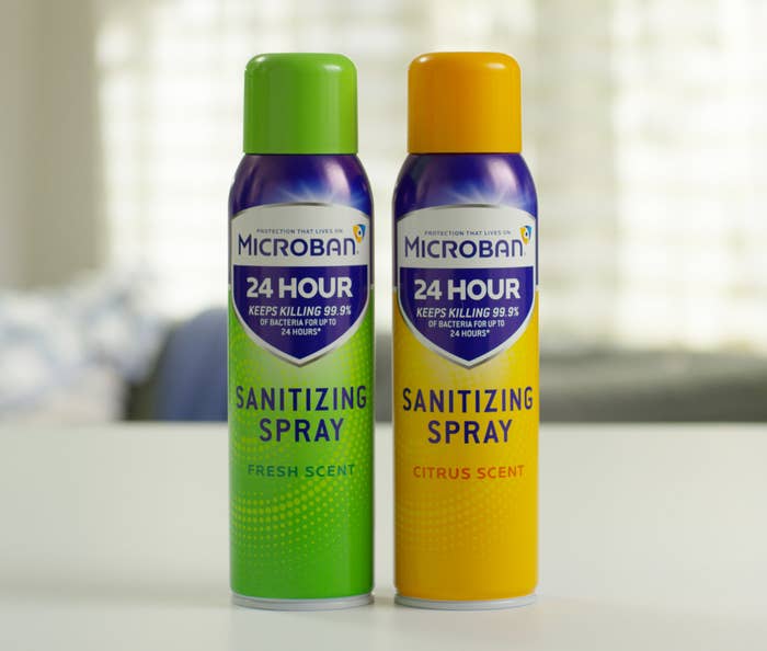 Two cans of Microban Sanitizing Spray sit on a counter.
