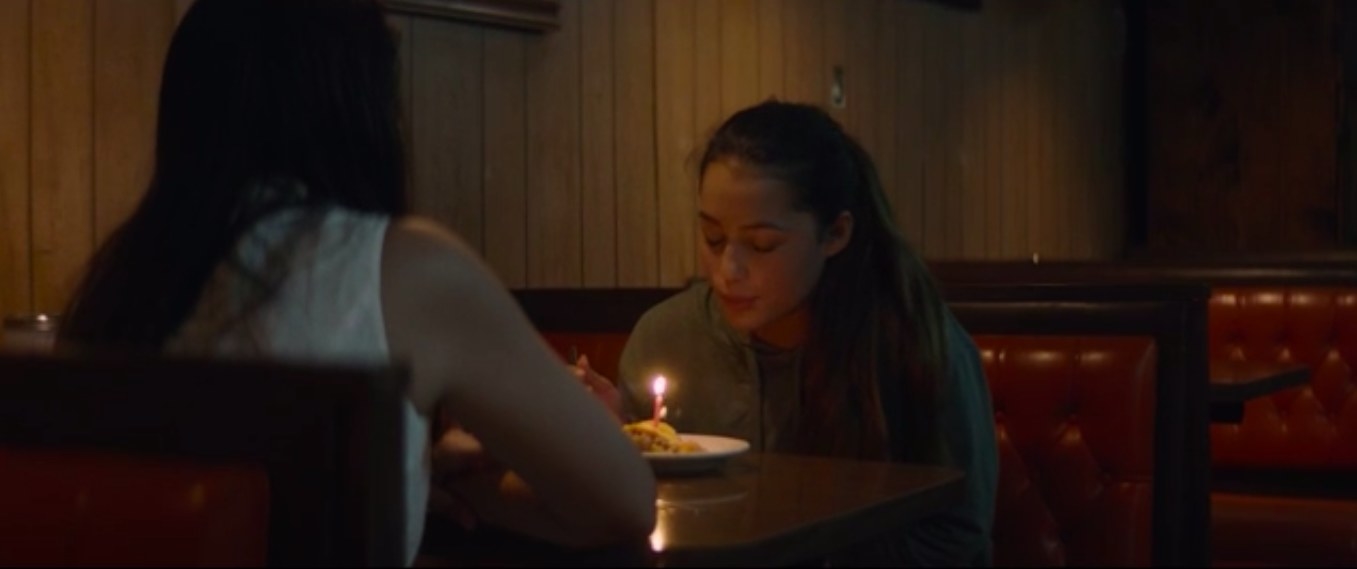 Erica Muñoz (Ana Alvarez) sitting at a diner booth with Izzy Hau&#x27;ula (Izzy Alvarez), blowing out a birthday candle in &#x27;Lone Gone By.&#x27;