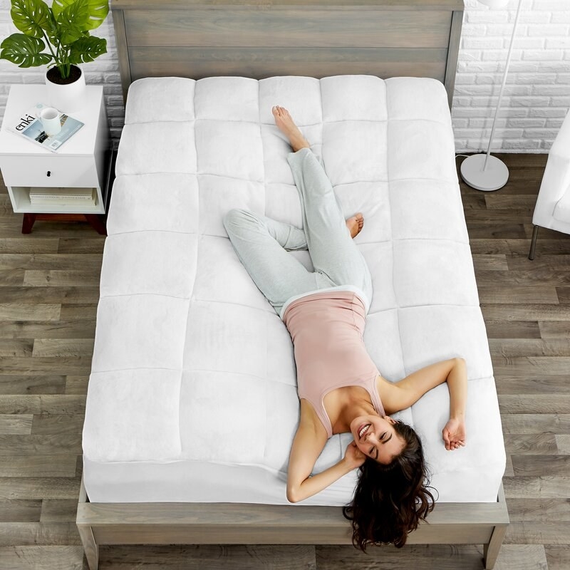 The mattress pad, which is white and quilted, and wraps around the edges of the mattress like a fitted sheet