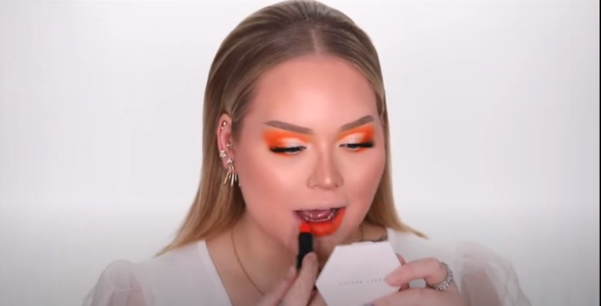 Nikkie de Jager applying orange lipstick to match her eyeshadow 