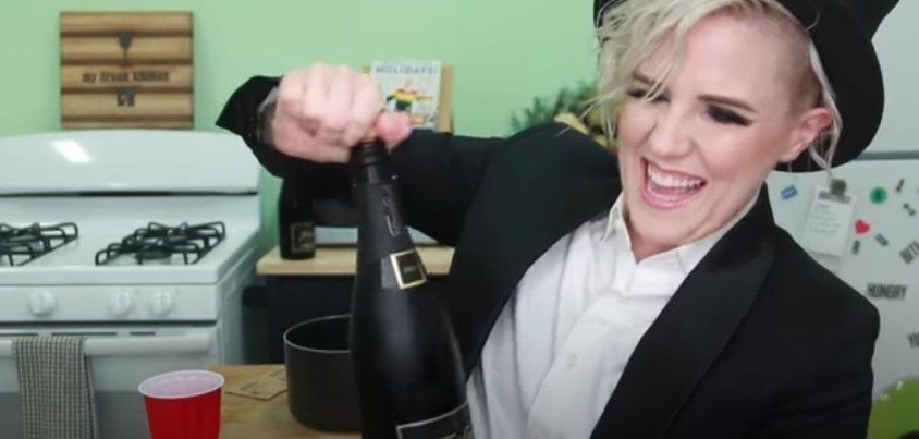 Hannah Hart in her kitchen holding a bottle of wine 