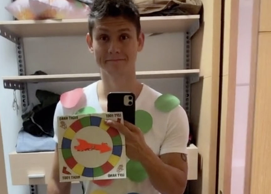 A man holds the board for the game Twister with colored dots attached to his shirt
